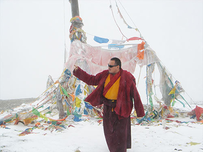 Arik Rinpoche in snow storm near prayer flags